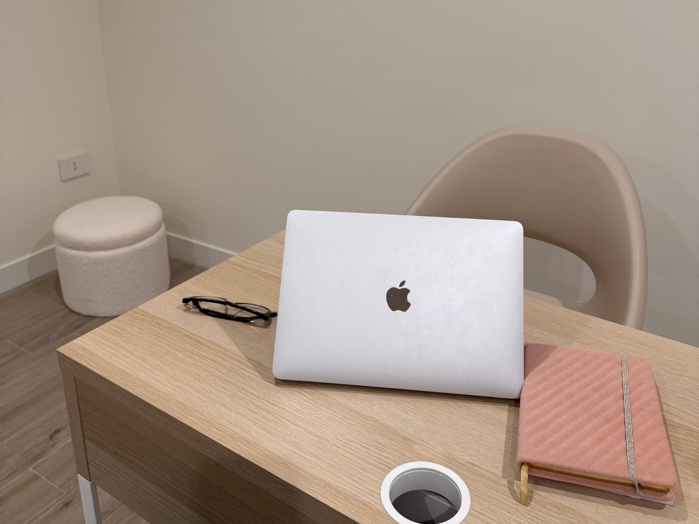 Scrivania con computer portatile, occhiali e un'agenda rosa
